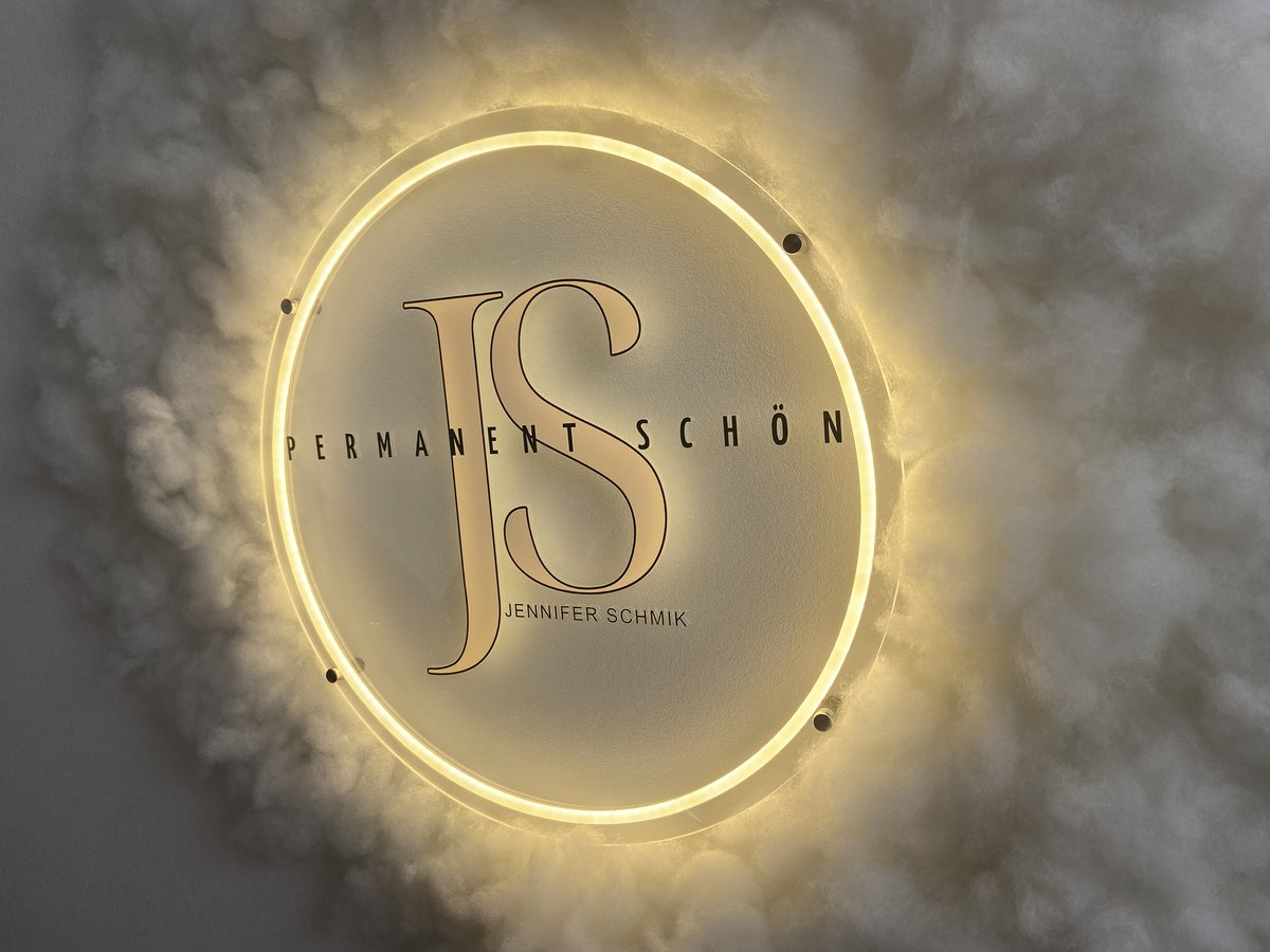 Studio Permanent Schön JS in Dörpen – beleuchtetes Logo im Empfangsbereich